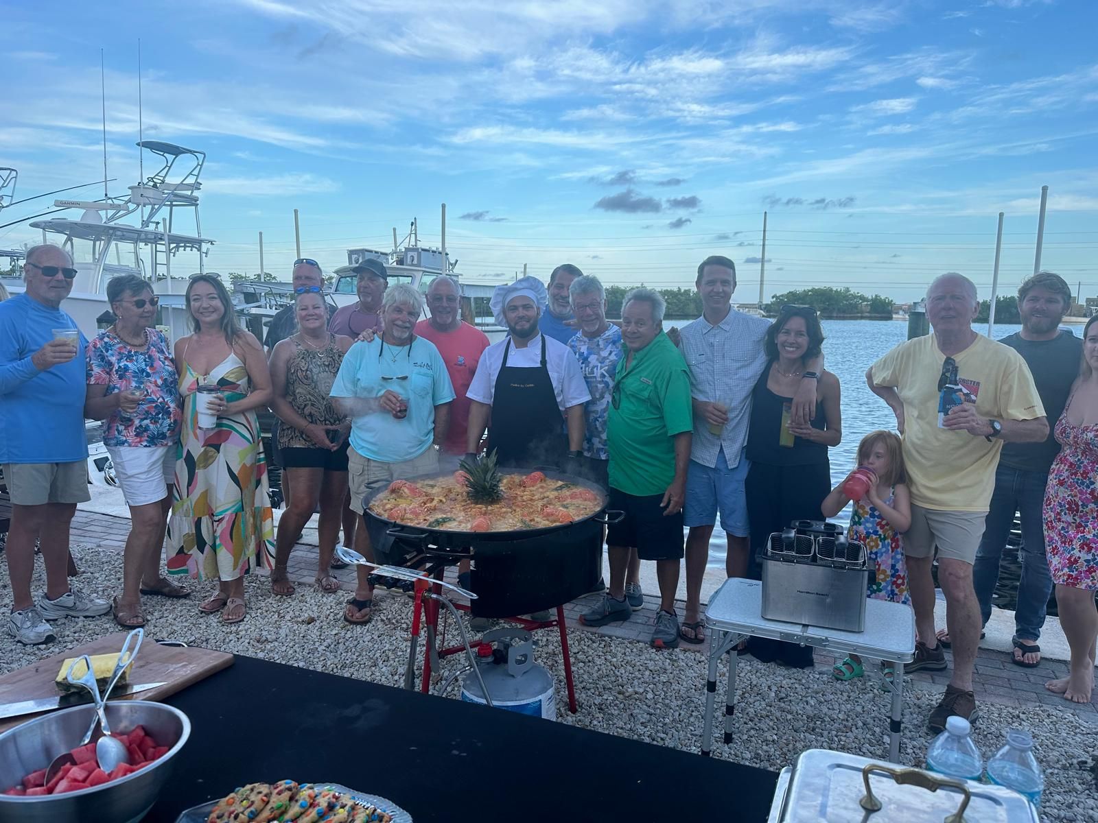 Invitados alrededor de la paella en una fiesta en el muelle